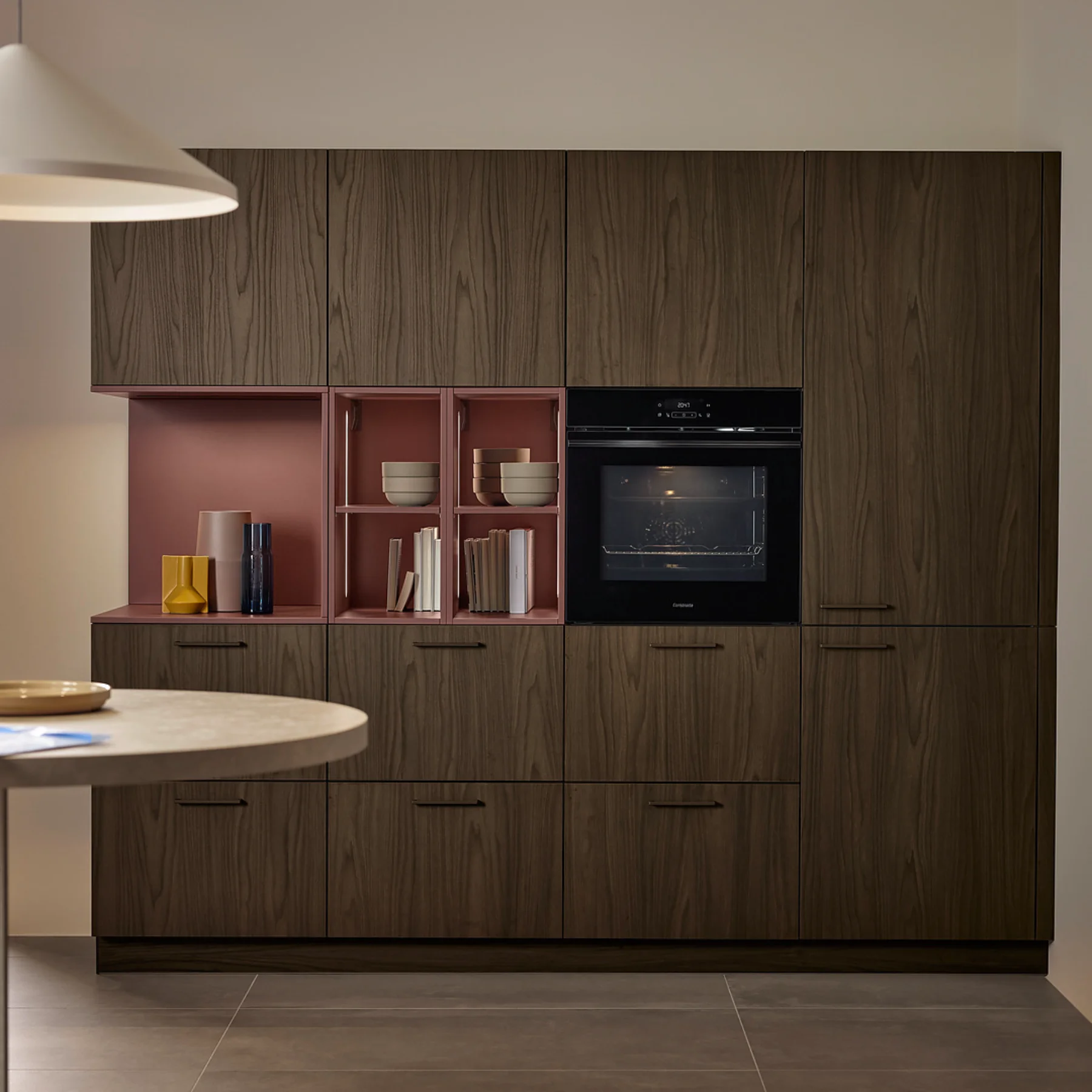 Moderna cucina a L Nolte con finitura SOFT LACK rosso henné e frontali in legno LEAF Noce Marone